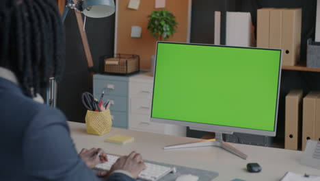 man working at a computer with a green screen monitor in modern office