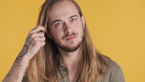 caucasian young man preening his hair in front of the camera.