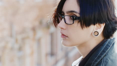 portrait of a pensive hipster woman sitting by the window dreaming she is dark-haired wear glasses