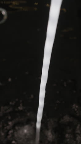 water pouring into a dark sink