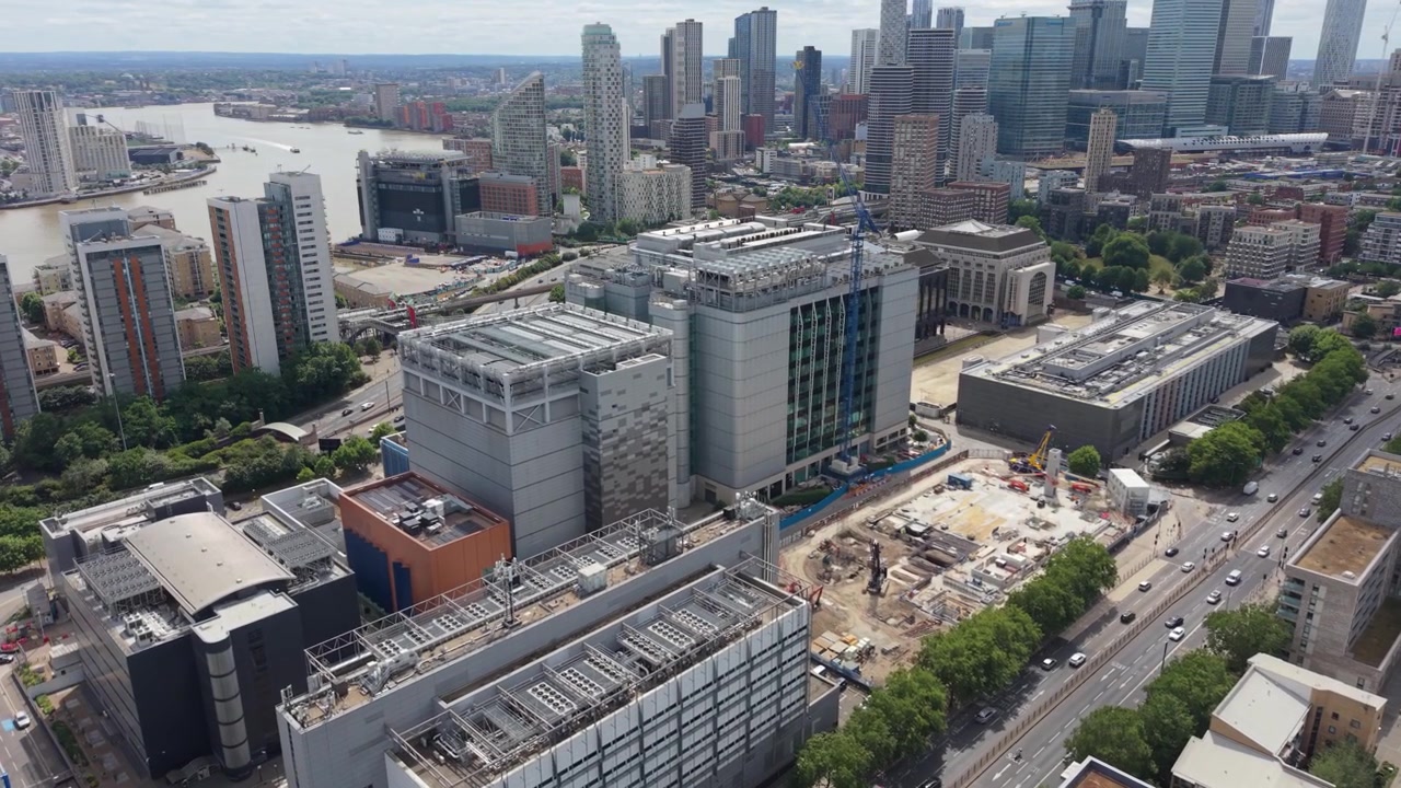 Luchtperspectief van een groot datacentercomplex in London Docklands overdag. Een grote bouwplaats naast het datacenter toont lopende bouwactiviteiten.