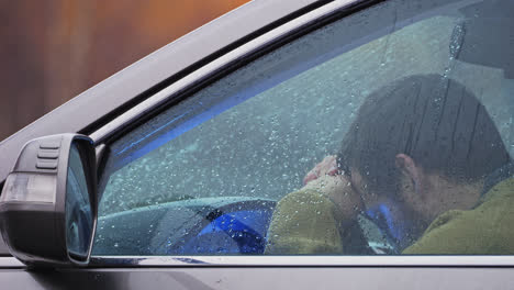 retrato cercano del conductor impaciente esperando en el coche en un clima lluvioso de otoño