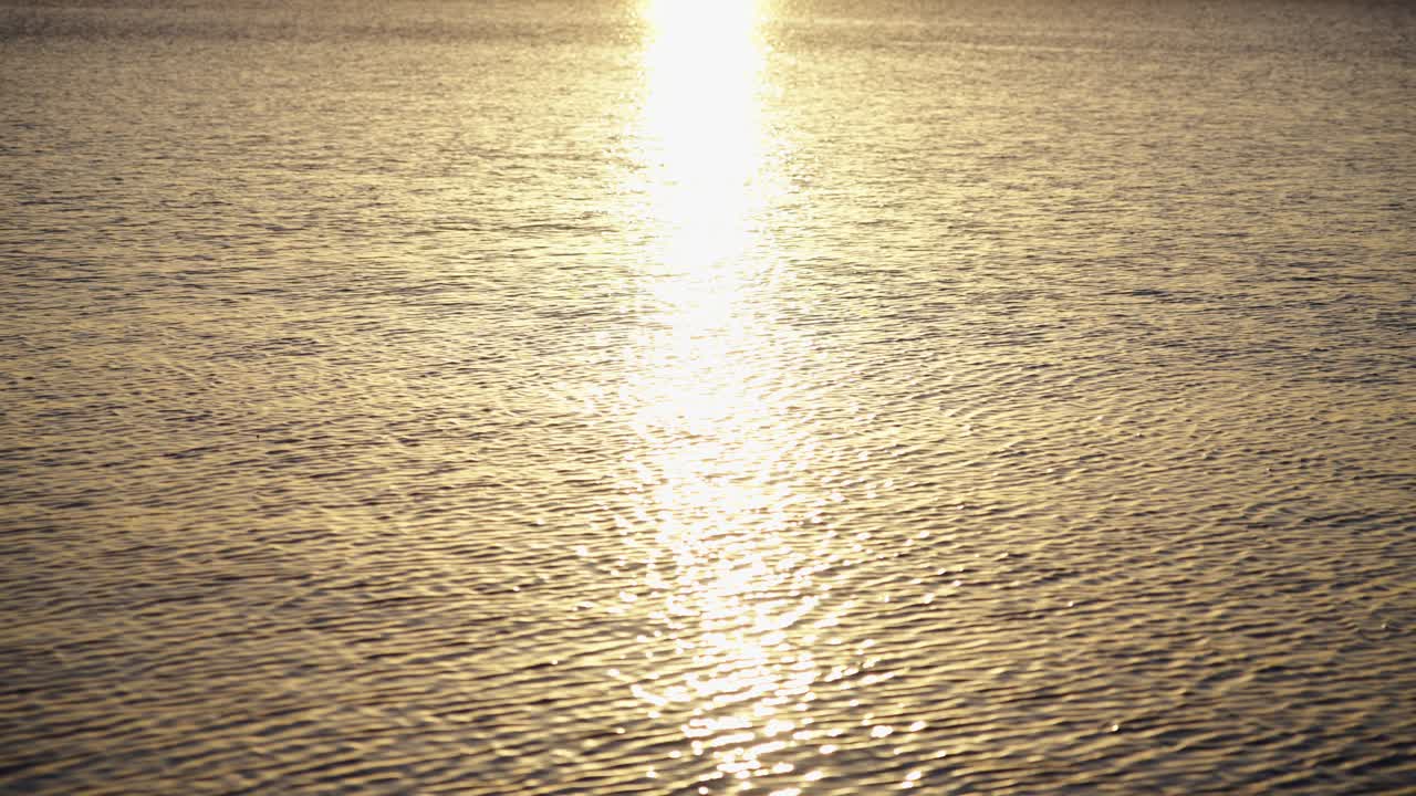 Gylden solrefleksion glimter på rolig vandoverflade