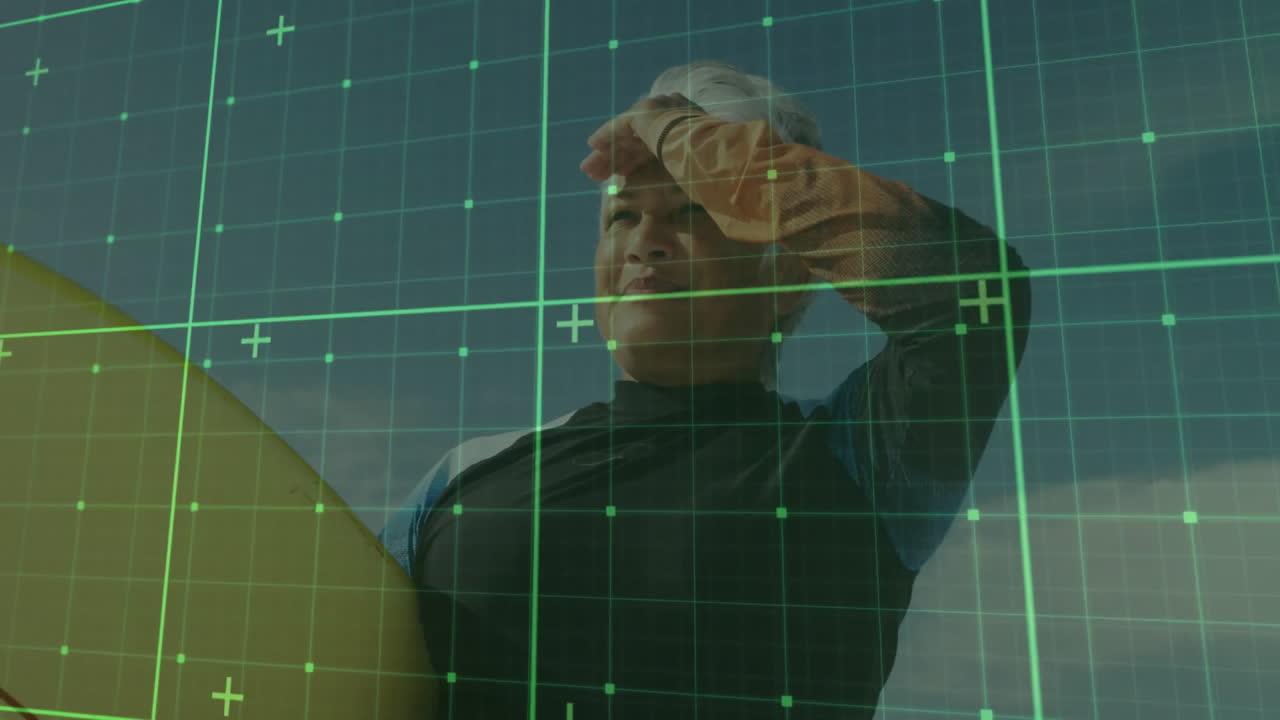 Senior woman in wetsuit shading eyes holding surfboard on coast, with technology grid overlay