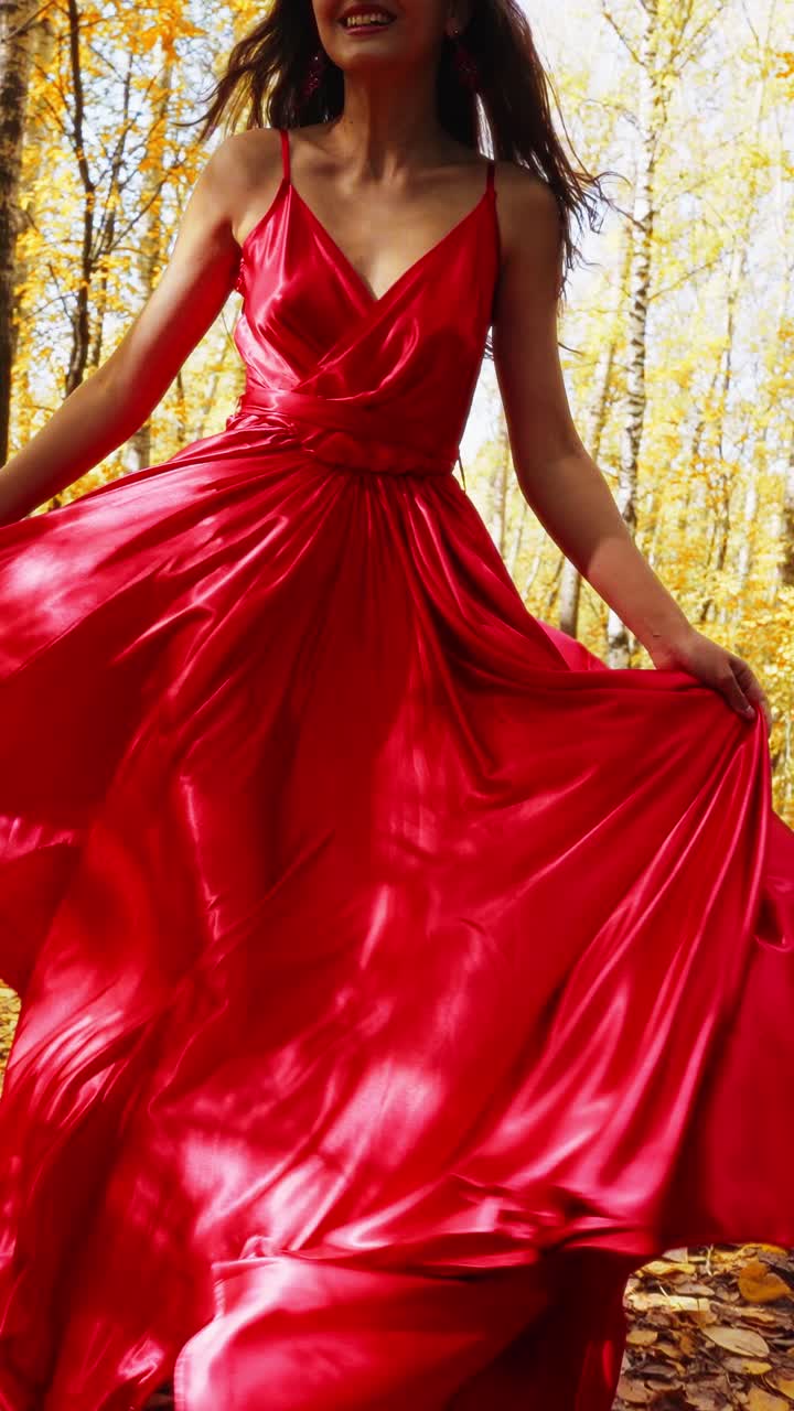 A graceful figure in a flowing red dress dances through a vibrant autumn forest, surrounded by golden leaves and illuminated by soft sunlight