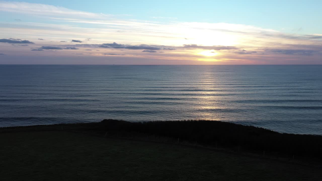 Una lenta ripresa aerea di un tramonto sulle scogliere del Devon meridionale vicino a Challyborough