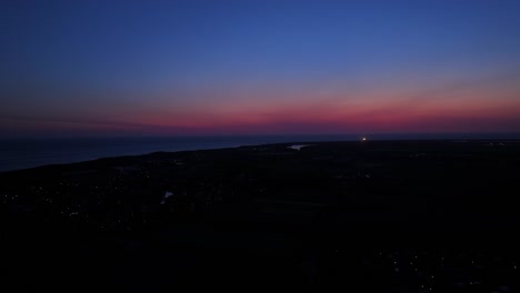 blinking lighthouse at the horizon after a colorful sunset above dutch coastline