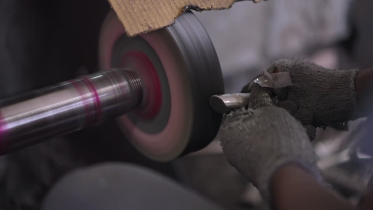 Using a belt sander to produce steel pan cookware in a factory