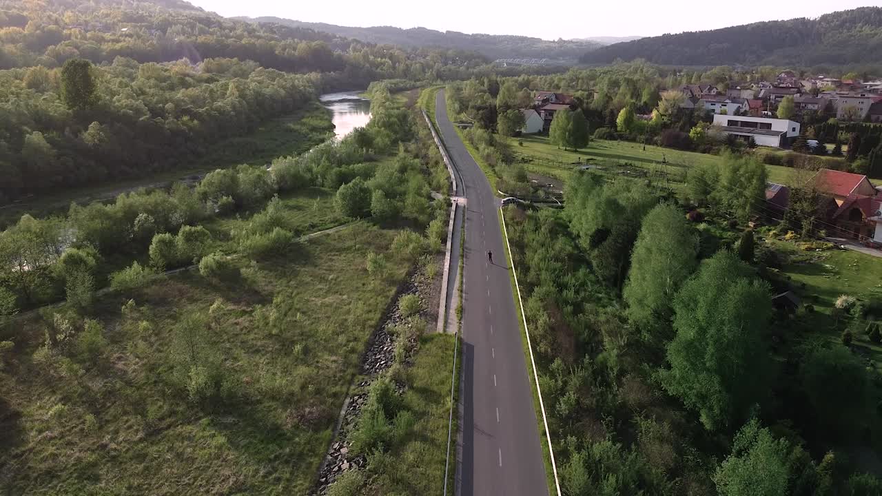 niño patinando sobre ruedas en el camino solitario de la puesta del sol