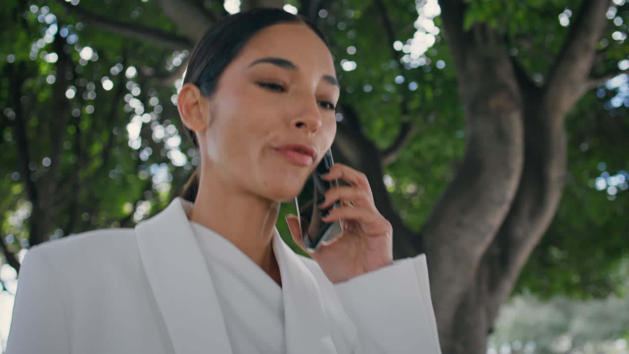 Joyful brunette talking phone walking city park close up. Cheerful woman calling