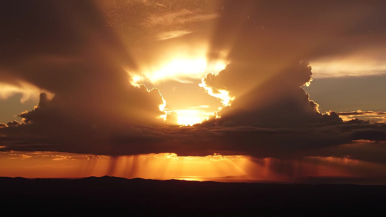 Raios de sol dourados atravessando nuvens de tempestade dramáticas ao pôr do sol