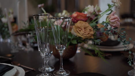 vasos de cristal y arreglos florales apagados en un lugar académico oscuro para una fiesta de cena fina