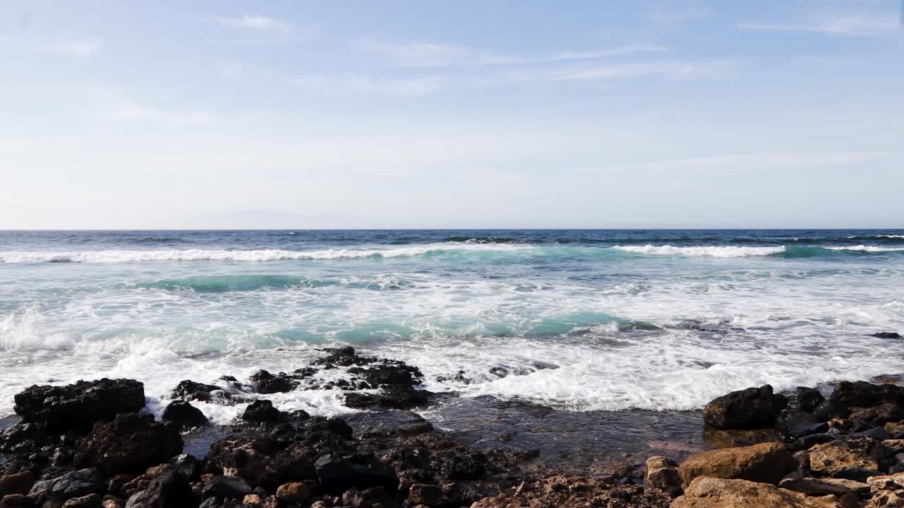 belas ondas pequenas durante um dia ensolarado na playa de las americas, tenerife