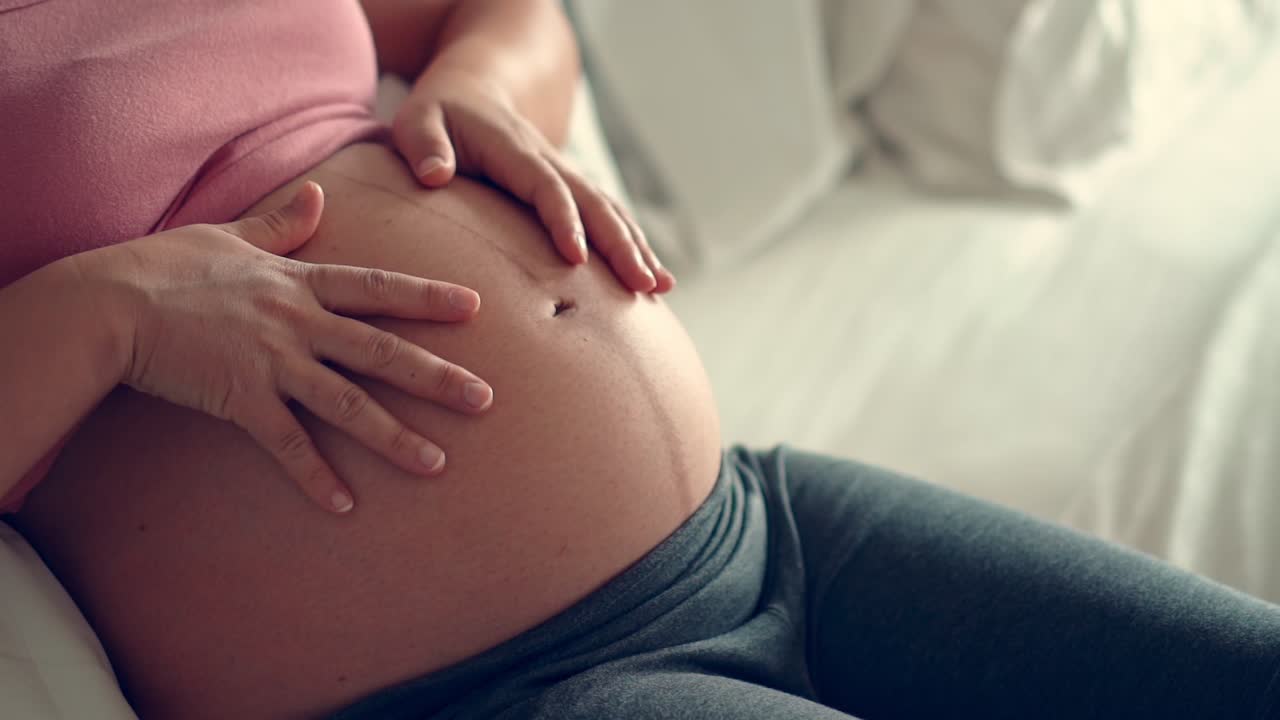Mujer embarazada feliz y esperando un bebé en casa