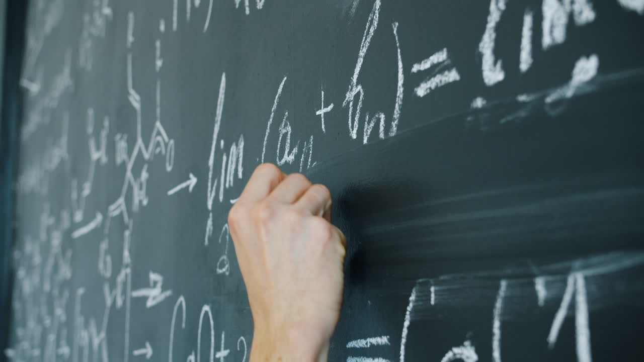 Person Writing Equations on a Chalkboard