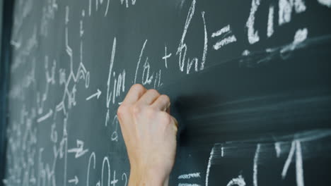person writing equations on a chalkboard