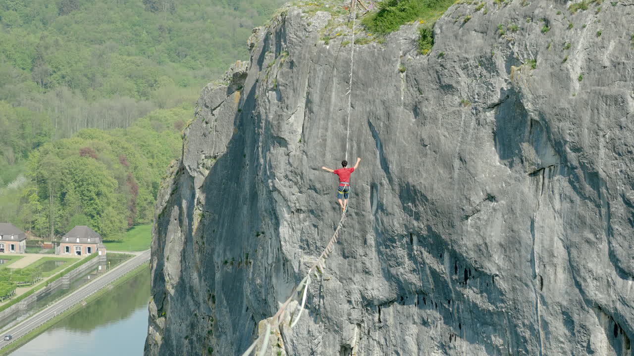 atleta tratando de mantener el equilibrio sobre una línea floja sobre un acantilado