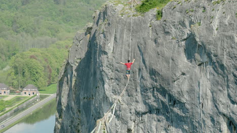 athlete trying to balance on slack line over cliff