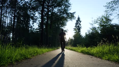 person walking through a forest path at sunset