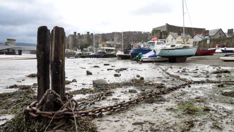 Viejo-Muelle-Abandonado-Podrido-Escombros-De-Madera-Y-Cadenas-Oxidadas-En-La-Costa-Del-Puerto-Del-Castillo-De-Conwy