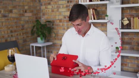 animación de corazones rojos sobre hombre caucásico abriendo caja de regalos roja en una cita de video