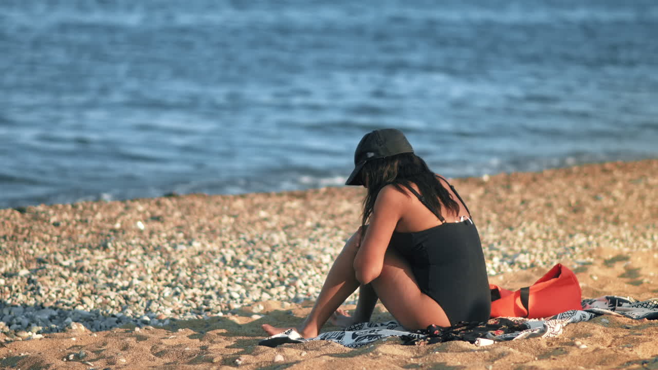 Sitting woman on the Mediterranean sea coast in Barcelona, Spain