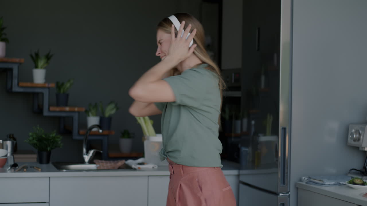 Donna che balla in cucina mentre ascolta musica