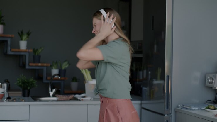 Donna che balla in cucina mentre ascolta musica