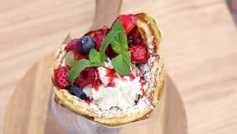 gofre en un vaso de vidrio decorado con crema batida, fresas, arándanos y carne picada