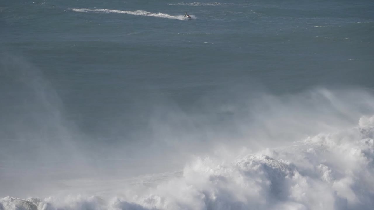 Enormous waves crashing against the shore in Nazare, Portugal, showcasing the power of the ocean