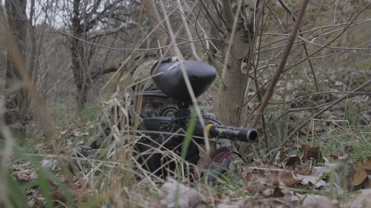 잔디에서 페인트볼 선수가 느린 동작으로 목표를 설정합니다.