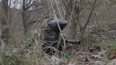 jugador de paintball en la hierba apuntando en cámara lenta