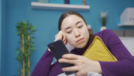 아시아 여성이 전화로 문자 메시지를 보면서 분위기는 떨어집니다.