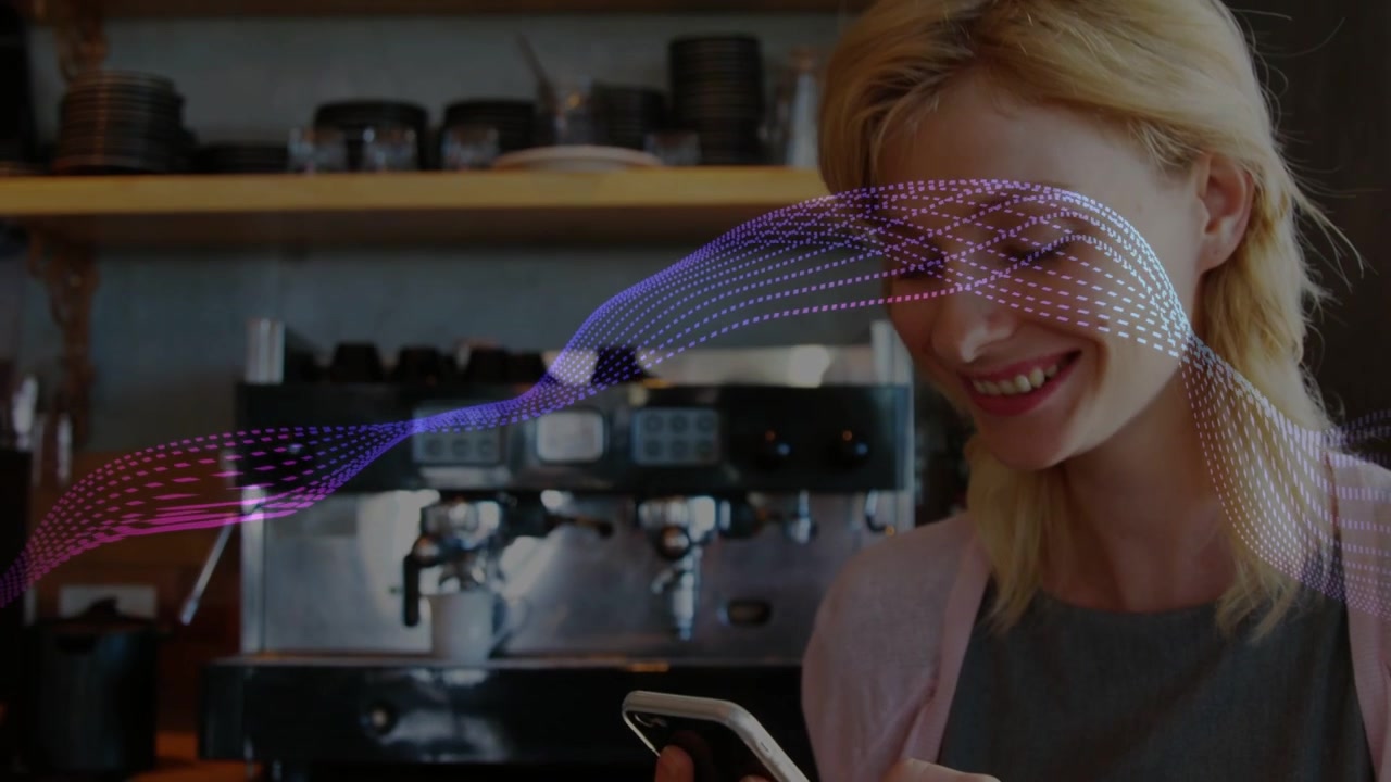 Barista che tocca il telefono al bancone del bar, con un'onda a puntini che scorre sullo schermo mentre legge e sorride