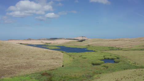 Blue-Sky-Over-Swan-Lake-With-Green-Grass-On-Hills-In-Northland,-North-Island,-New-Zealand