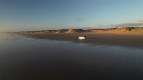 car is driving on long 90 mile beach in new zealand