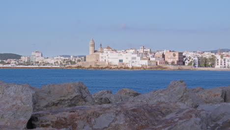 lapso de tiempo de un pueblo pesquero costero con una iglesia rodeada de rocas, mientras las nubes proyectan sombras en movimiento sobre los edificios