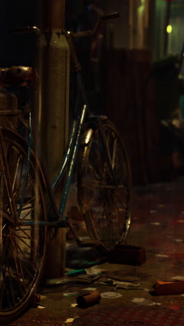 bike parked next to trash can on rainy night in asian city