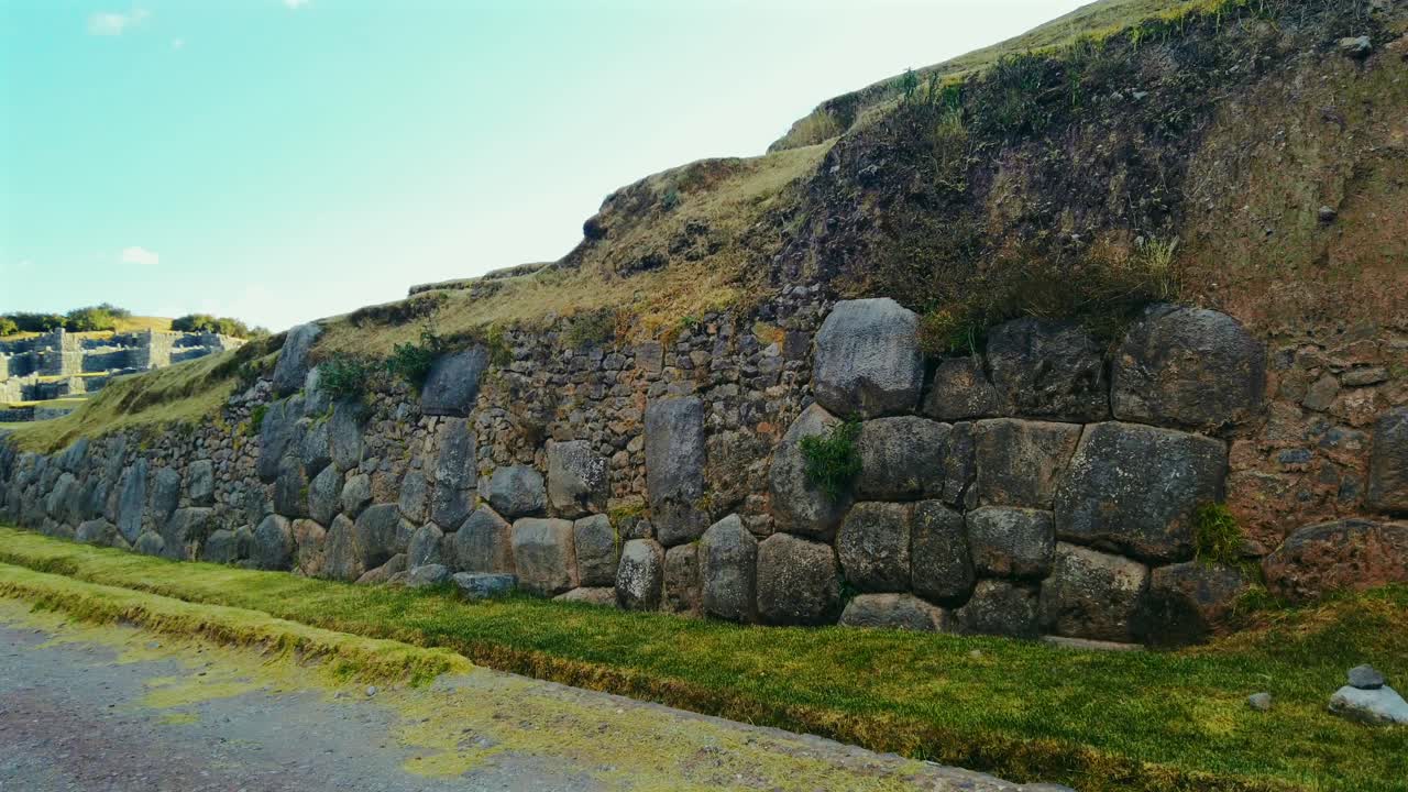 Solo woman traveler walks through the ancient ruins of Sacsayhuamán near Cusco, Peru. Giant massive stone walls close up view. No tourists cinematic shot