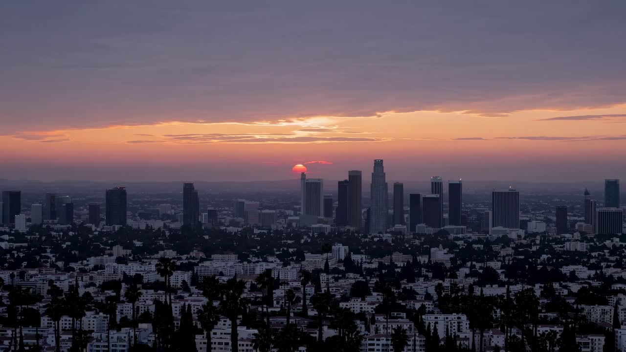 Urban skyline illuminated by sunset, with vibrant hues reflecting off buildings, as the sun sinks below the horizon, enhancing the evening ambiance and cityscape beauty