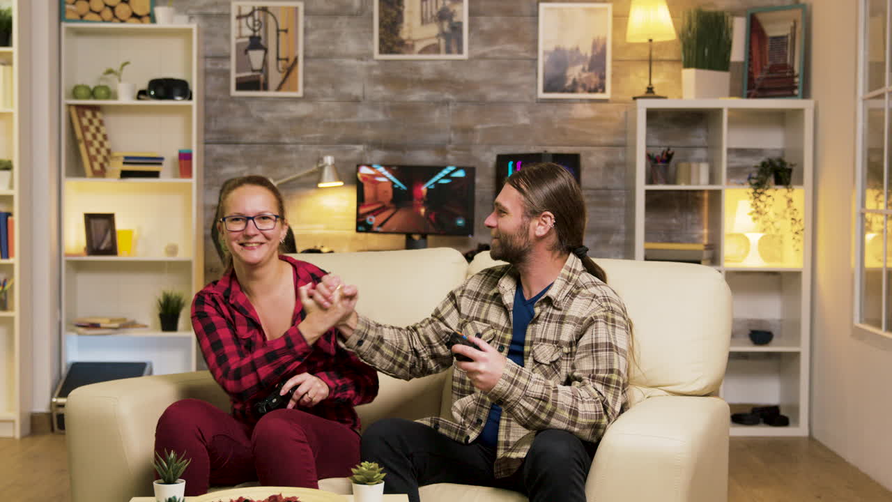 Couple gaming at home, celebrating a win