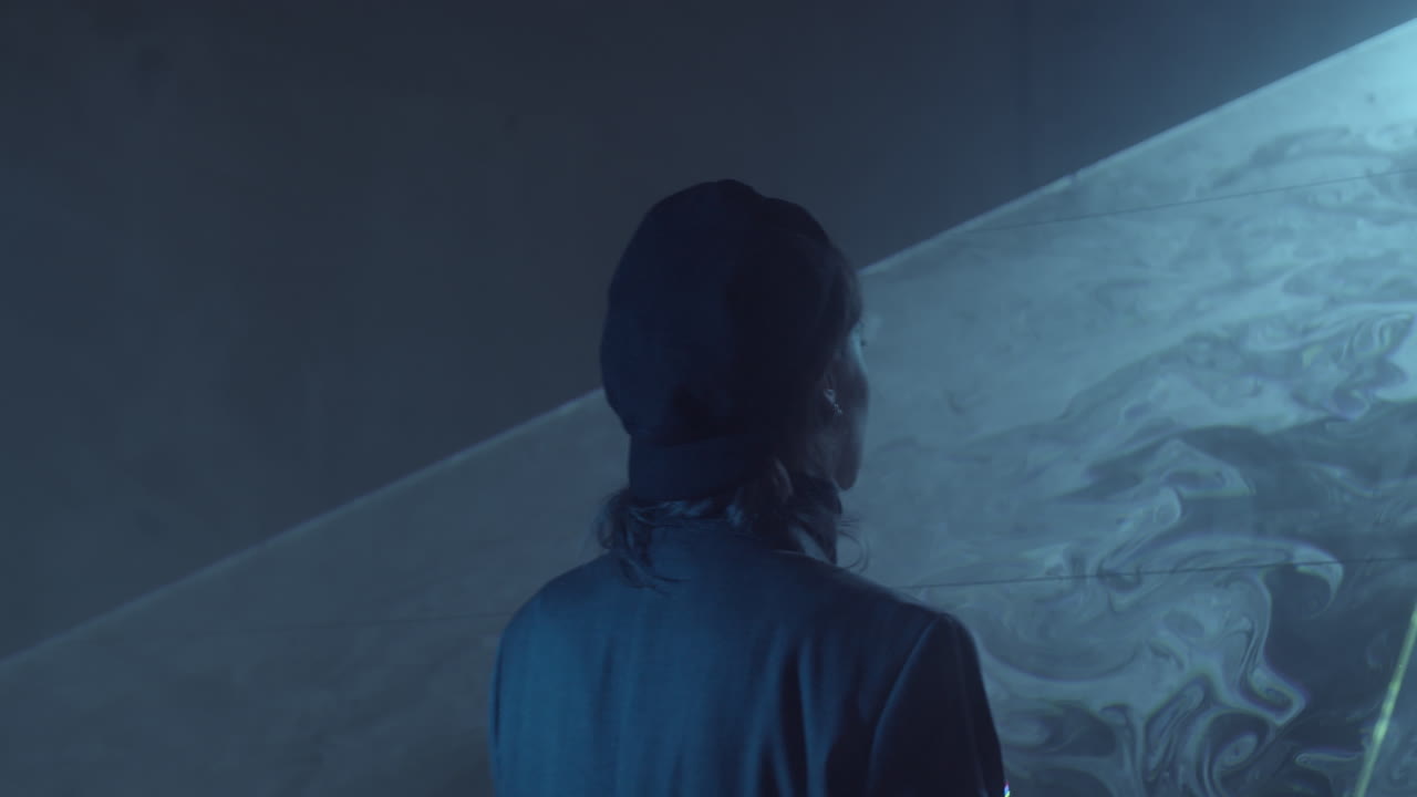 donna che attraversa un foglio piatto di luce laser in uno studio buio