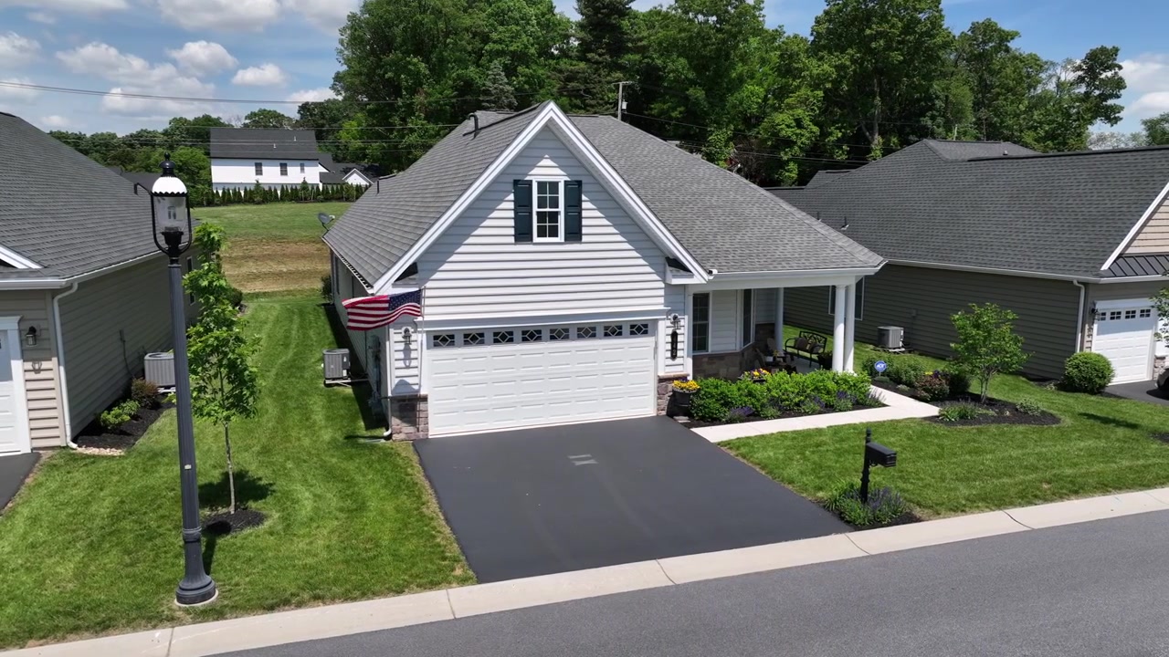 Bandeira americana orgulhosa tremulando em uma casa unifamiliar com garagem em um bairro suburbano recém-desenvolvido nos EUA. Lititz, Pensilvânia. Estados Unidos. Vista aérea.