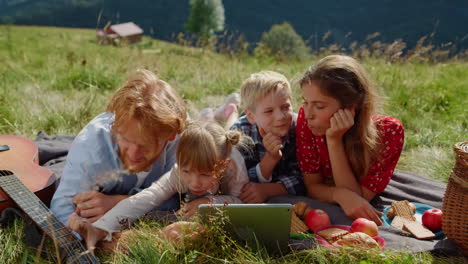 happy family rest tablet on green meadow sunny day close up. summer holiday.