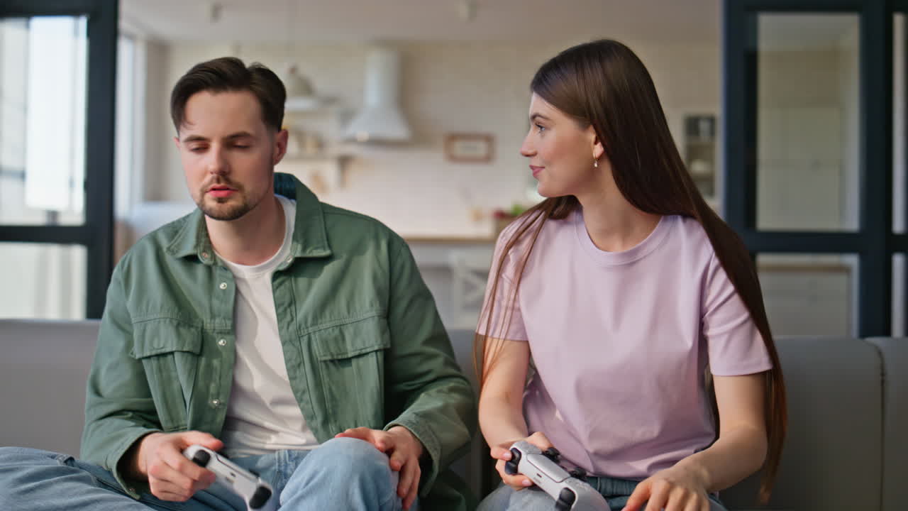 Focused friends playing video games using controllers sitting couch together
