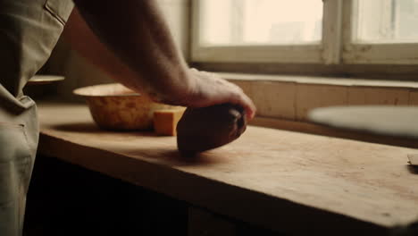 Man-getting-ready-for-handicraft-in-pottery.-Ceramist-sculpting-piece-of-clay