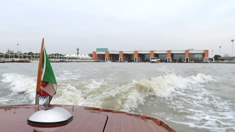 Taxi-boat-leaving-Marco-Polo-Airport-dock-area,-Venice,-Italy