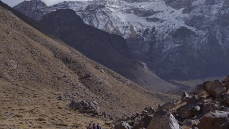 Trail-of-hikers-making-their-way-down-a-rocky-and-snowy-mountain