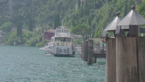 Ferry-De-Transporte-Público-En-El-Lago-De-Garda-En-Riva-Del-Garda-Norte-De-Italia-En-Cámara-Lenta,-Primer-Plano-Con-Montañas-En-El-Fondo