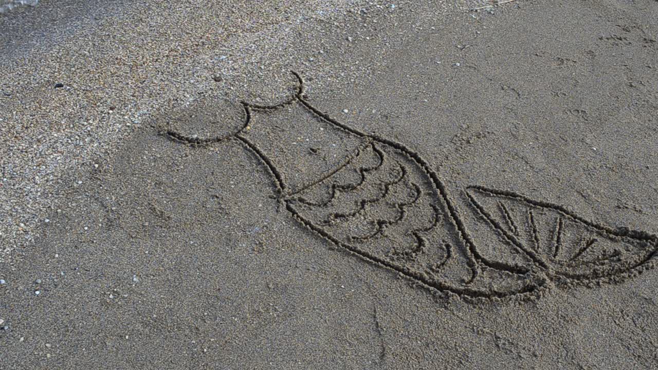 Il disegno della sirena sulla spiaggia. Servizio fotografico sulla spiaggia